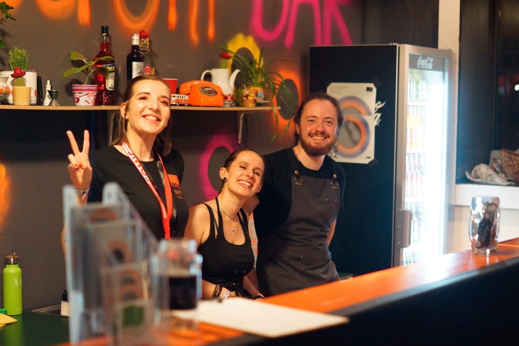 Bar im Festivalzentrum mit drei lächelnden Menschen